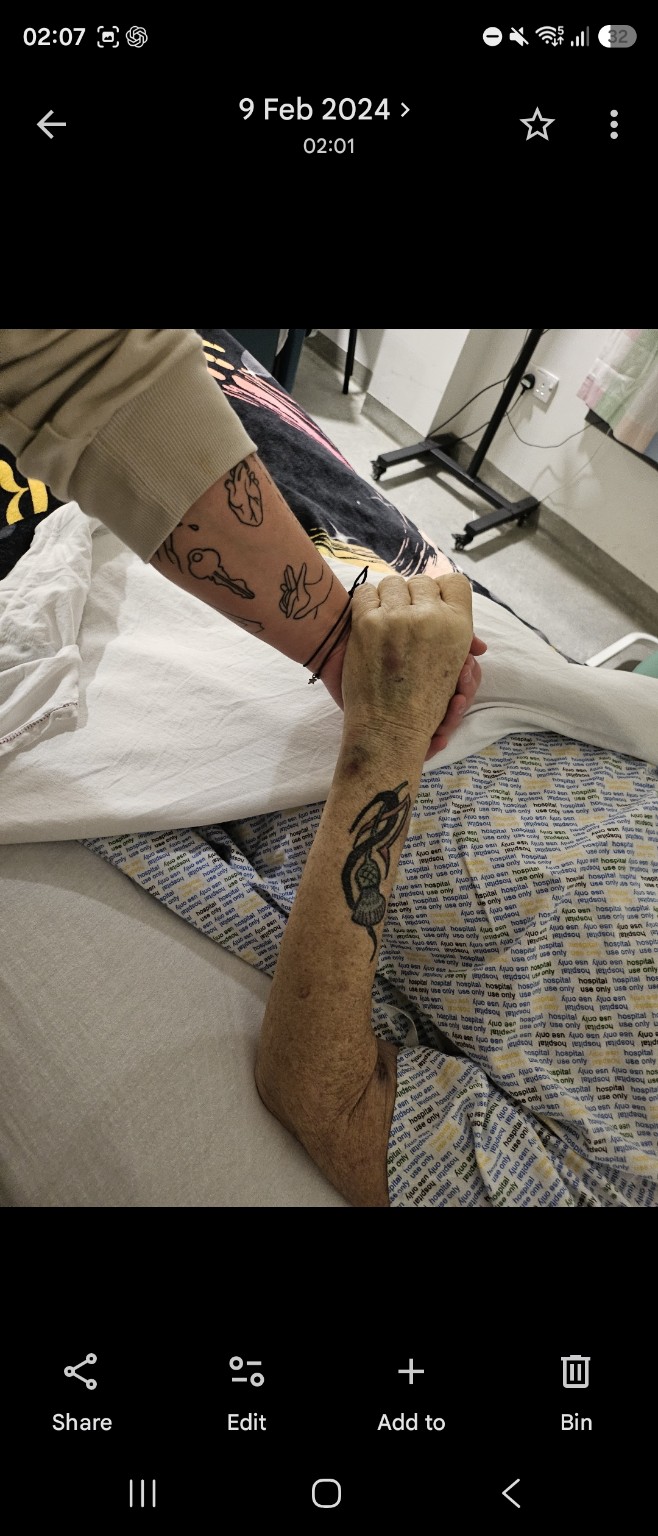 Family hands gently holding a loved one’s hand at the bedside